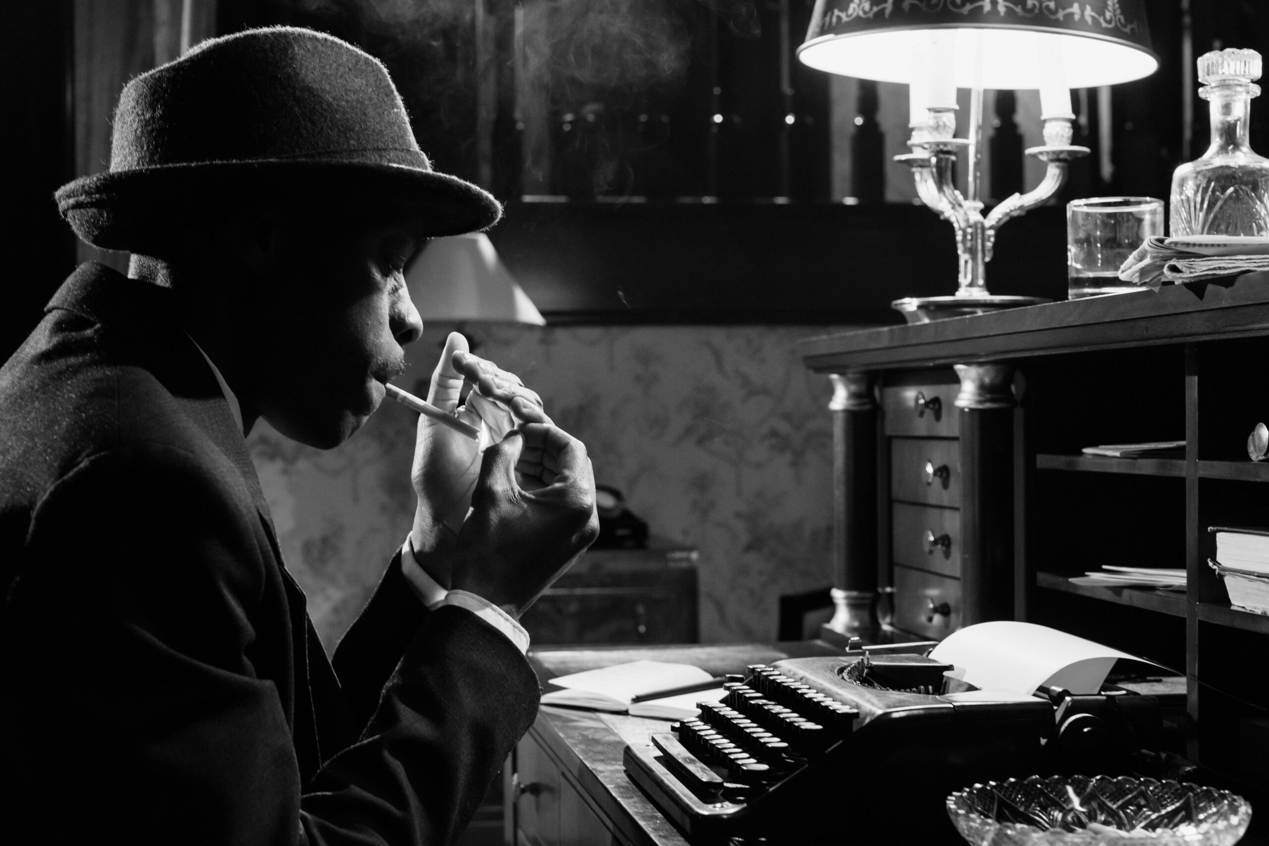 A noir detective at a typewriter. Black and white.