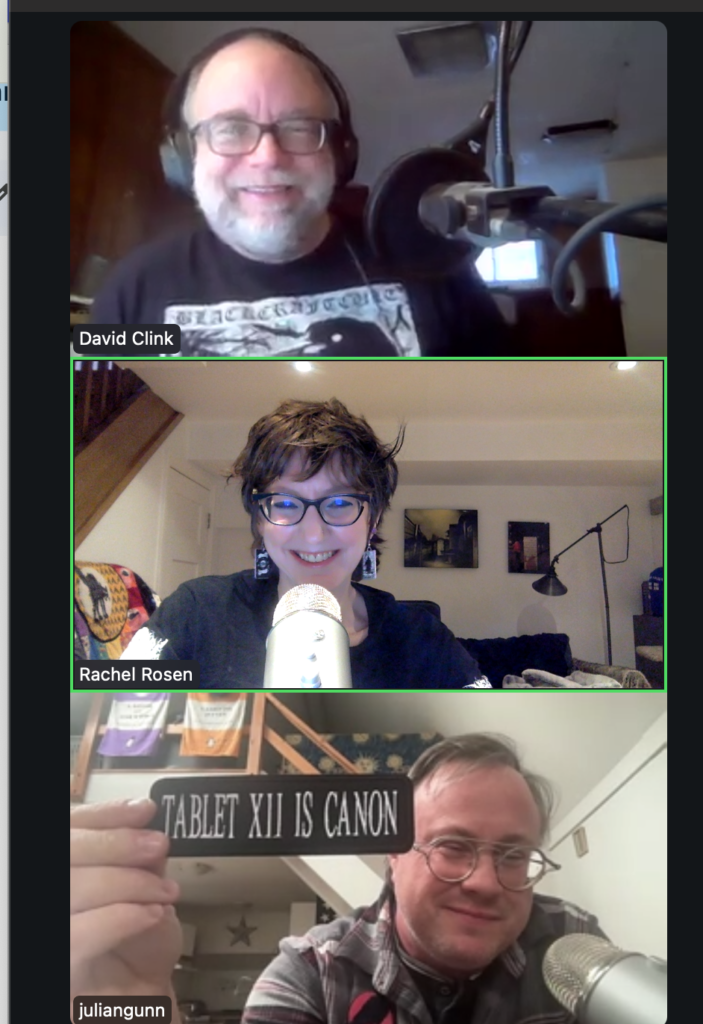 A screen shot of the Zoom call showing David, a white man with glasses and a beard wearing headphones, Rachel, a white woman with glasses, and Julian, a white man with glasses holding up a patch that says "Tablet XII is canon."